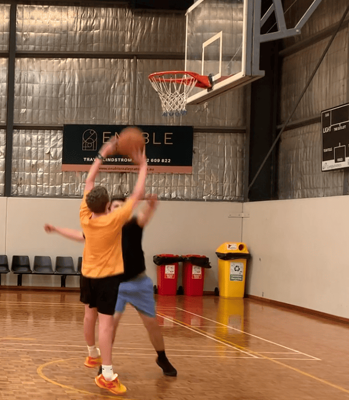 teenager with disability and support worker playing basketball